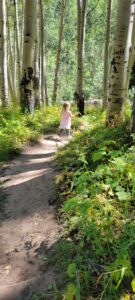 A young girl running ahead on a trail through the forest. 