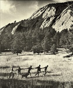 Black-and-white photo of people with an off-leash dog in a meadow outside Boulder, Colorado. Taken by Harold Malde in 1967, courtesy Carnegie Library for Local History, Boulder.