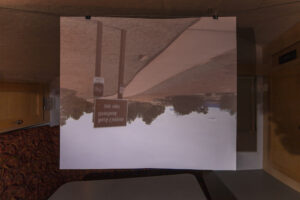 An screen shows an upside down image of a road with an informational road sign.